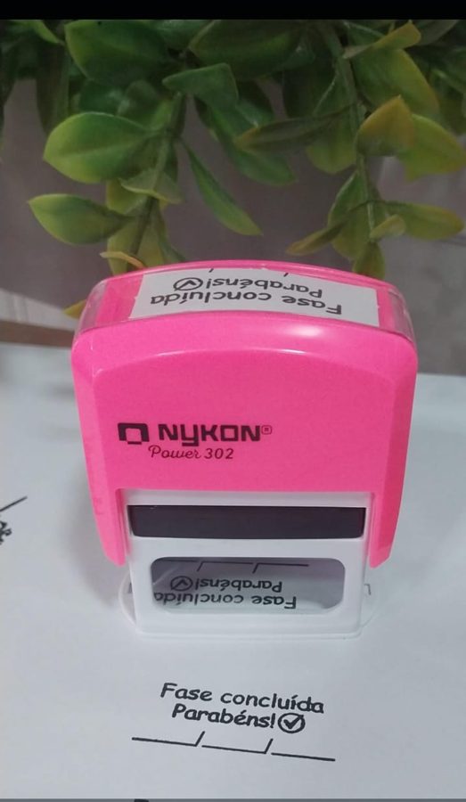 Carimbo rosa Nykon Power 302 com a impressão “Fase concluída, Parabéns!”